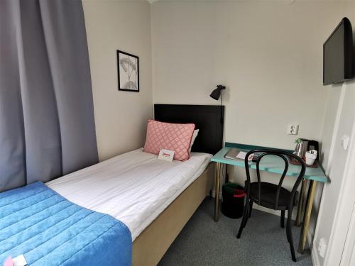 a small bedroom with a bed and a desk at 2Home Hotel Gävle in Gävle
