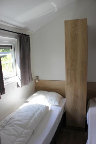een bed in een kamer met een raam en een bed sidx sidx sidx bij De Bijsselse Enk, Noors chalet 8 in Nunspeet