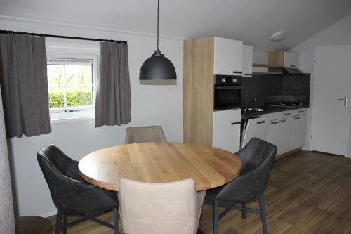 een keuken en eetkamer met een houten tafel en stoelen bij De Bijsselse Enk, Noors chalet 9 in Nunspeet