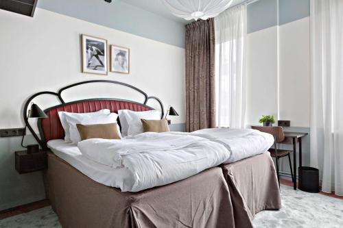 a bedroom with a large bed with a red headboard at Hotel Giò; BW Signature Collection in Solna