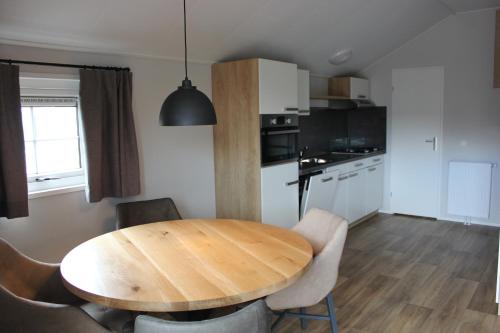 een keuken en eetkamer met een houten tafel en stoelen bij De Bijsselse Enk, Noors chalet 12 in Nunspeet