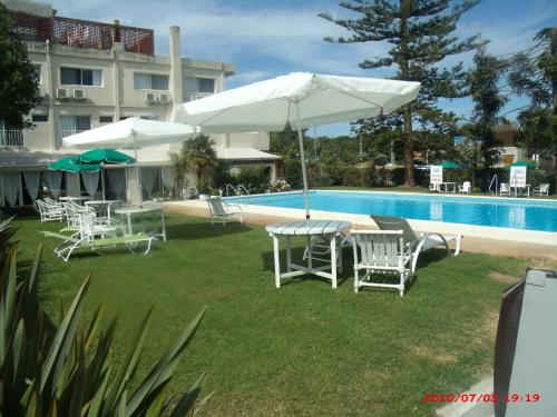 a group of chairs and umbrellas next to a pool at Hotel Puesta del Sol in Punta del Este