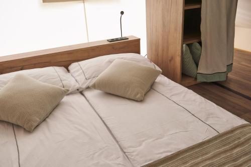 a white bed with two pillows on top of it at Lakeside Petzen Glamping in Unterlibitsch