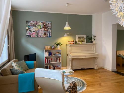 a living room with a couch and a piano at Privé sauna & terras - Aachen Vaals Drielandenpunt in Vaals