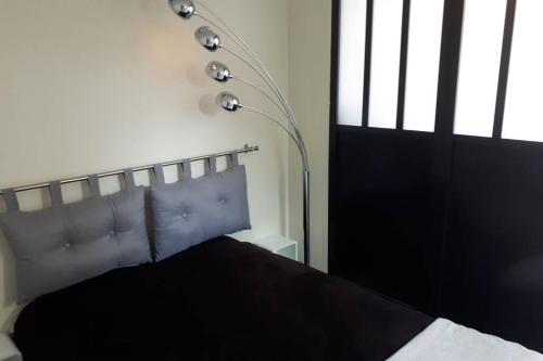 - une chambre avec un lit noir et une lampe dans l'établissement Maisonnette à 100 M de Tarbes sud, à Laloubère