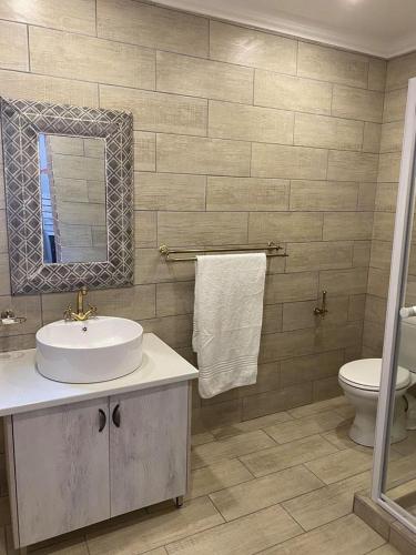 a bathroom with a sink and a toilet and a mirror at The Perfect Corner Guesthouse in Bethlehem