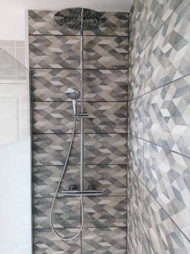 une douche dans une salle de bain avec un mur carrelé dans l'établissement Chez Magali et Aymeric, à La Méaugon