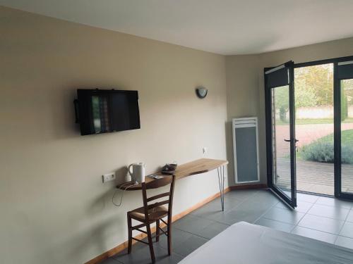 a room with a table and a television on the wall at La Grange de l’Ouche in Saint-Parize-le-Châtel
