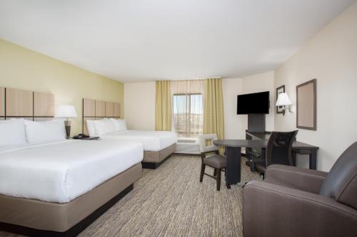 a hotel room with two beds and a desk at Candlewood Suites Pueblo, an IHG Hotel in Pueblo