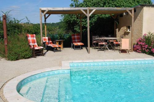 einen Pool mit Stühlen, einem Tisch und einer Terrasse in der Unterkunft Gîte à la ferme avec piscine in Bernadets-Debat