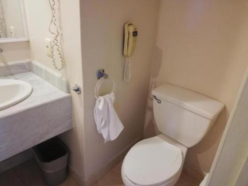 a bathroom with a toilet and a phone on the wall at Hotel Fortin Plaza in Oaxaca City