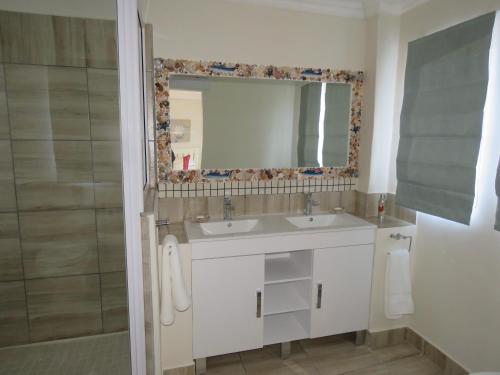 a bathroom with a sink and a mirror and a shower at Dolphin Place in Port Shepstone