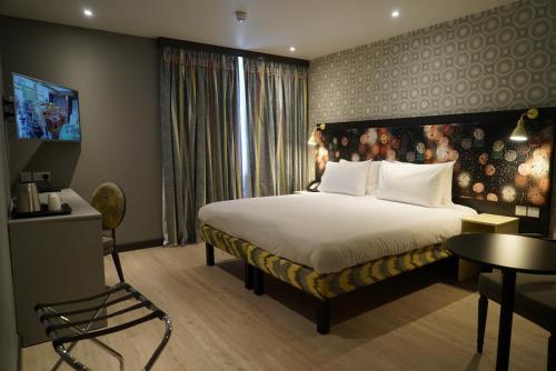 a hotel room with a large bed and a large window at Best Western Plus London Wembley Hotel in London