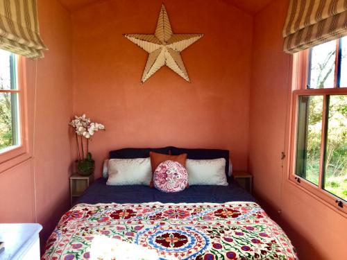 The Oaks Glamping - Pips Cabin في Colkirk: غرفة نوم بسرير نجمة على الحائط