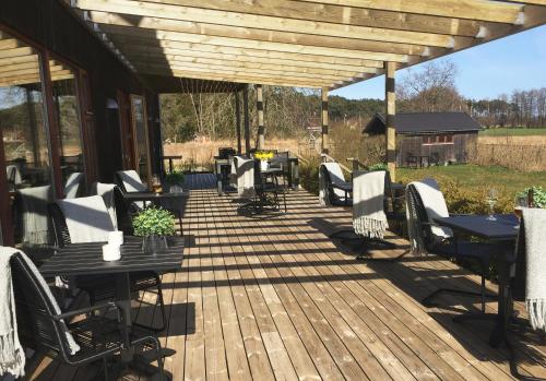 a wooden deck with tables and chairs on it at Bodelssons by the Sea in Tosteberga