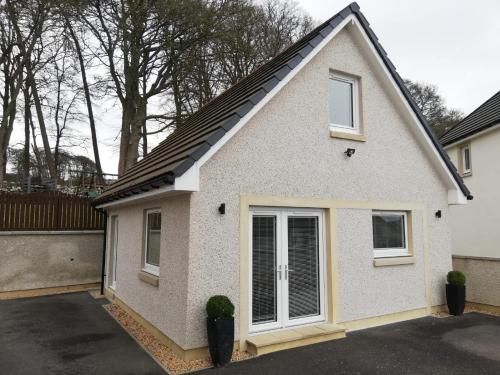a small white house with a garage at Appin Apartment in Inverness