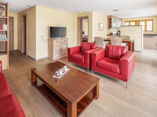 Sala de estar con 2 sillas rojas y mesa de centro en Apartment Chalet Smaragd-3 by Interhome, en Grindelwald