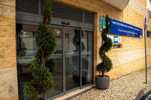 a store front with two potted trees outside of it at HI Parque das Nações – Pousada de Juventude in Lisbon