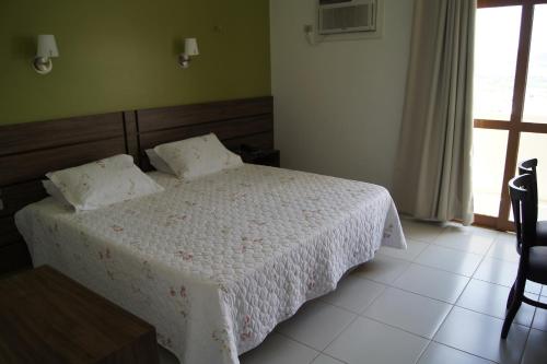 a bedroom with a white bed and a window at Panorama Hotel in Juazeiro do Norte