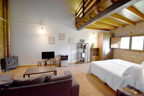 een slaapkamer met een bed, een bank en een tv bij HOTEL RURAL A VELHA FABRICA in Valverde del Fresno