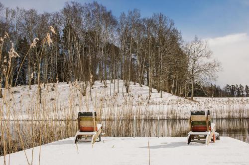 two chairs sitting in the snow next to a fence at Pūjalgi in Ēdole