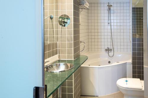 a bathroom with a tub and a sink and a toilet at Hotel Plaza in A Coruña