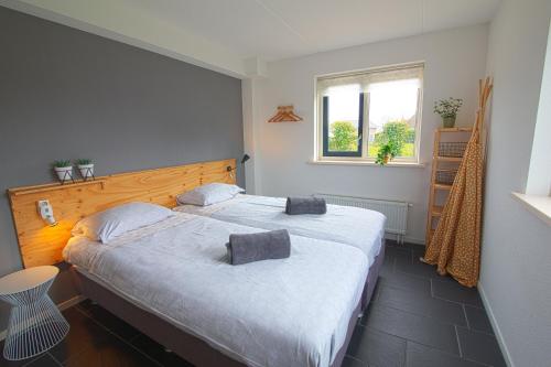 1 dormitorio con 2 camas y ventana en Luxus Familienvilla mit Jacuzzi & Sauna, en Tzummarum