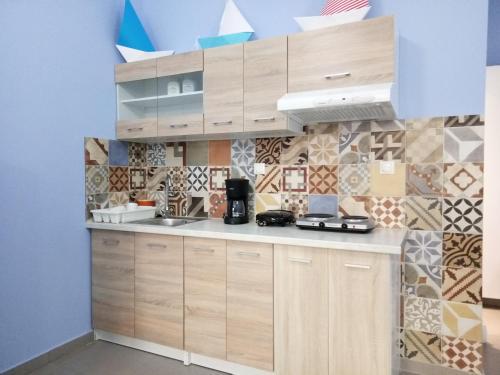 a kitchen with wooden cabinets and a tiled wall at Ilida Kourouta Studios in Kourouta