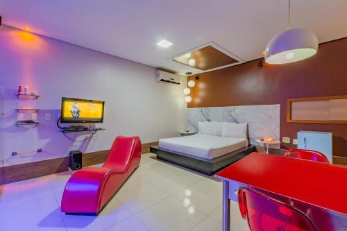 a hotel room with a bed and a red chair at Assahi Motel (Adult Only) in Fortaleza