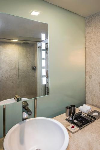 a bathroom with a white tub and a large mirror at The Park New Delhi in New Delhi