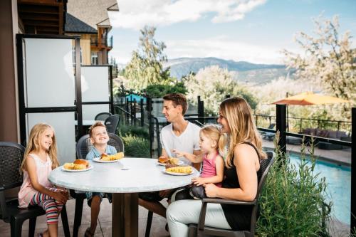 a family sitting at a table eating food on a patio at Summerland Waterfront Resort & Spa in Summerland