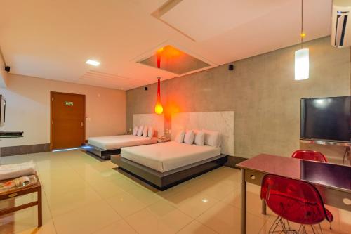 a bedroom with two beds and a flat screen tv at Assahi Motel (Adult Only) in Fortaleza