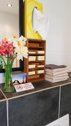 a counter with flowers in a vase and a mirror at Blue Wall BnB in Gebenstorf