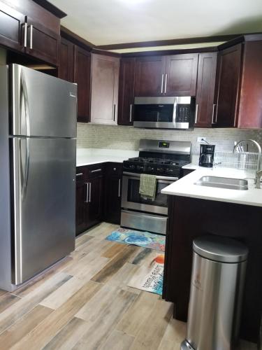 a kitchen with wooden cabinets and a stainless steel refrigerator at Inn The Town in Port Antonio