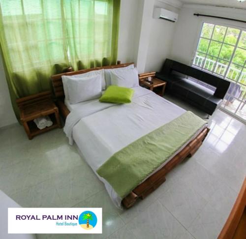 een slaapkamer met een groot bed met een groen kussen bij Casa Royal Palm Inn in San Andrés