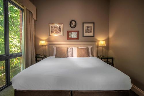a bedroom with a large white bed and a window at Majestic Old Lion Apartments in Adelaide
