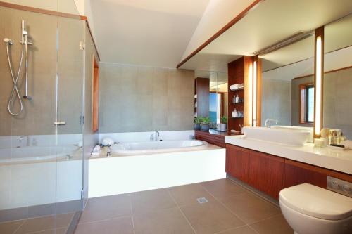 a bathroom with a tub and a sink and a toilet at Yacht Club Villas in Hamilton Island