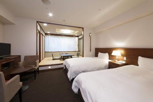 a hotel room with two beds and a television at Hakoneji Kaiun in Hakone