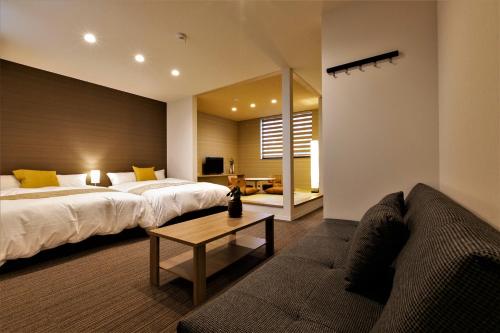 泉佐野市にあるアパートメントホテル ステイザ関西空港のベッド2台とソファが備わるホテルルームです。