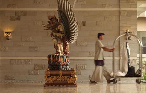 a man walking past a statue in a building at The Seminyak Beach Resort & Spa in Seminyak