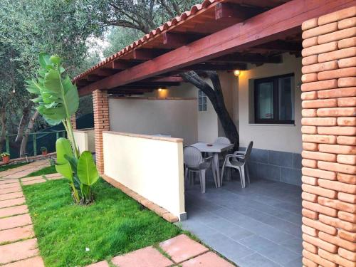 um pátio com uma mesa e cadeiras sob uma pérgola em Villa Oasi Naturale em Marina di Camerota