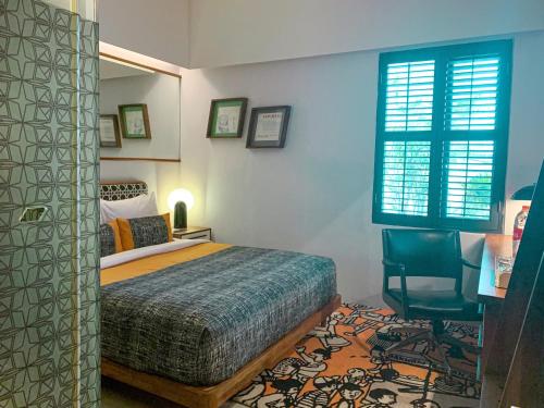 a bedroom with a bed and a chair and a window at Kosenda Hotel in Jakarta