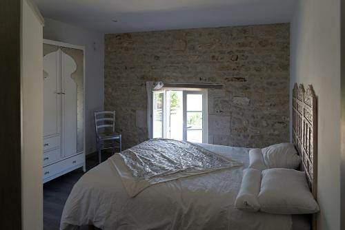 ein Schlafzimmer mit einem Bett und einer Ziegelwand in der Unterkunft La Maison d'Isabelle in Voissay
