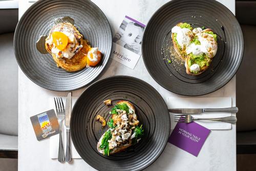 a table with three plates of food on it at Mercure Canberra Belconnen in Canberra