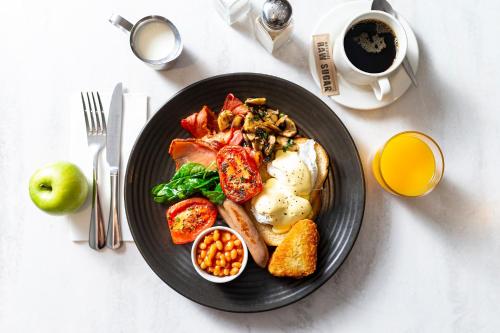 a plate of breakfast food on a table with a cup of coffee at Mercure Canberra Belconnen in Canberra