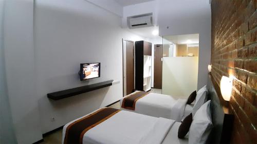 a hotel room with two beds and a tv at Xtra Hotel Bengkulu in Bengkulu