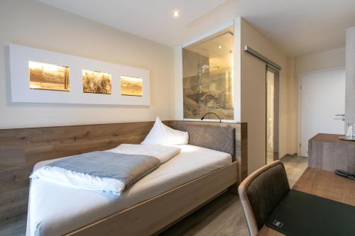 a bedroom with a bed and a desk and a window at Hotel am Wald in Bad Tölz