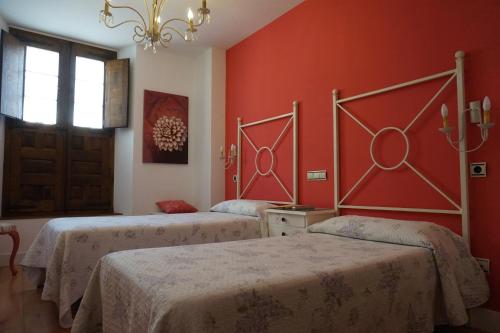 two beds in a room with red walls at Arganzón Plaza in La Puebla de Arganzón