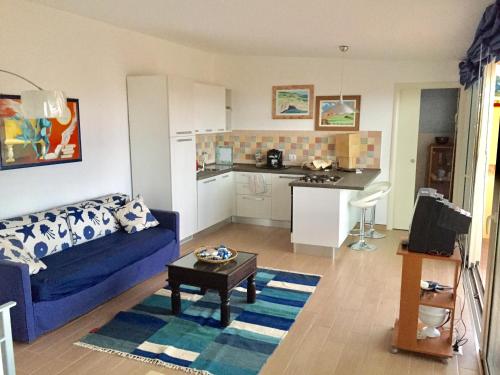 ein Wohnzimmer mit einem blauen Sofa und einer Küche in der Unterkunft Holiday Nizza House in Nizza di Sicilia