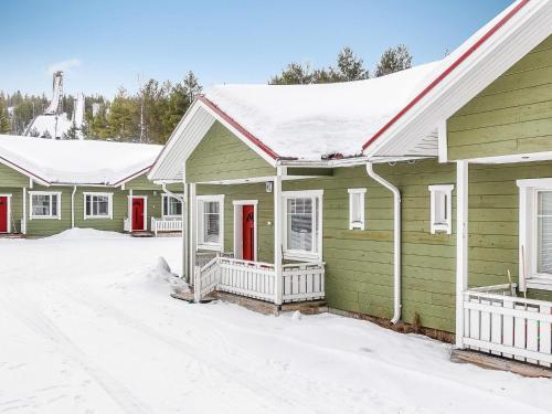 SaarenkyläにあるHoliday Home Huoneisto b1 by Interhomeの雪中の赤い扉が並ぶ緑の家
